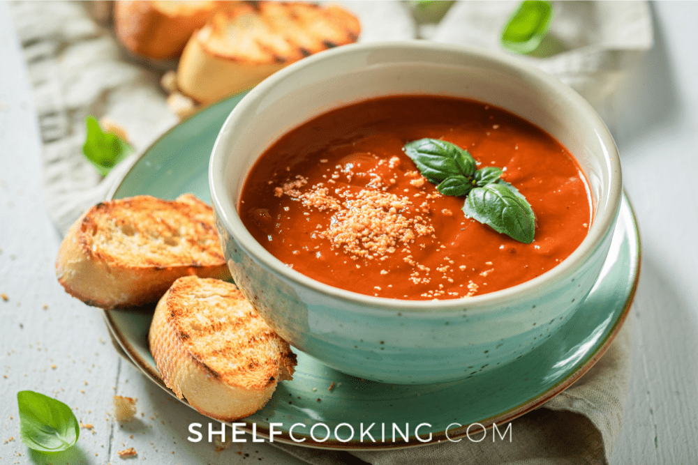 Image of Instant Pot tomato soup in a teal bowl with toasted bread on a plate. - Shelf Cooking