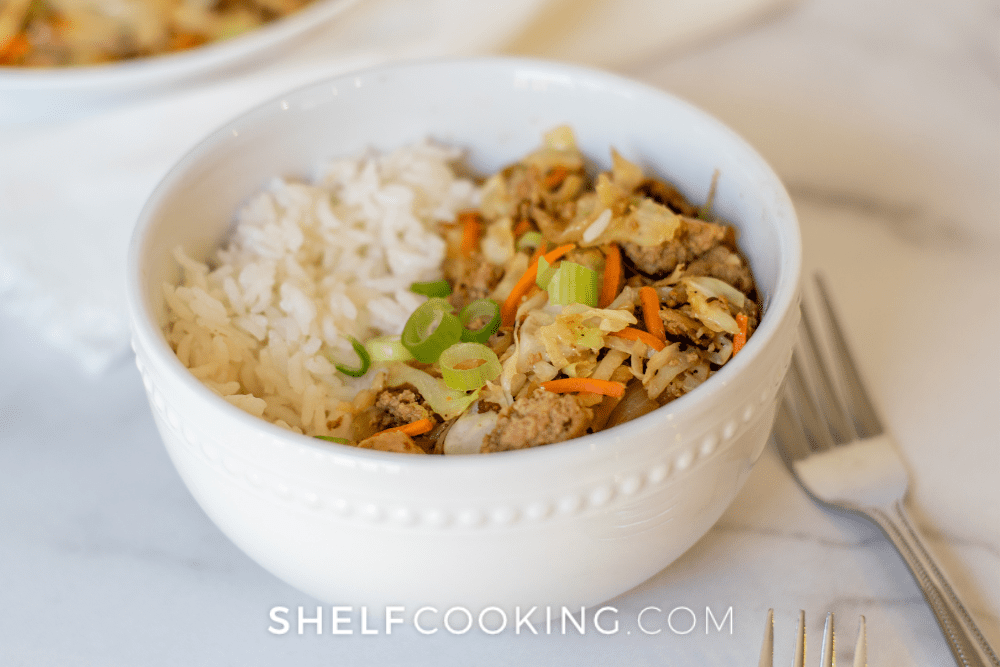 Image d'un bol de riz garni de viande hachée cuite et de salade de chou. - Étagère Cuisine