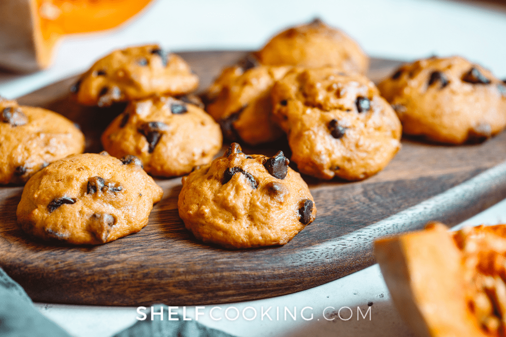 Wooden board topped with pumpkin chocolate chip cookies. - Shelf Cooking